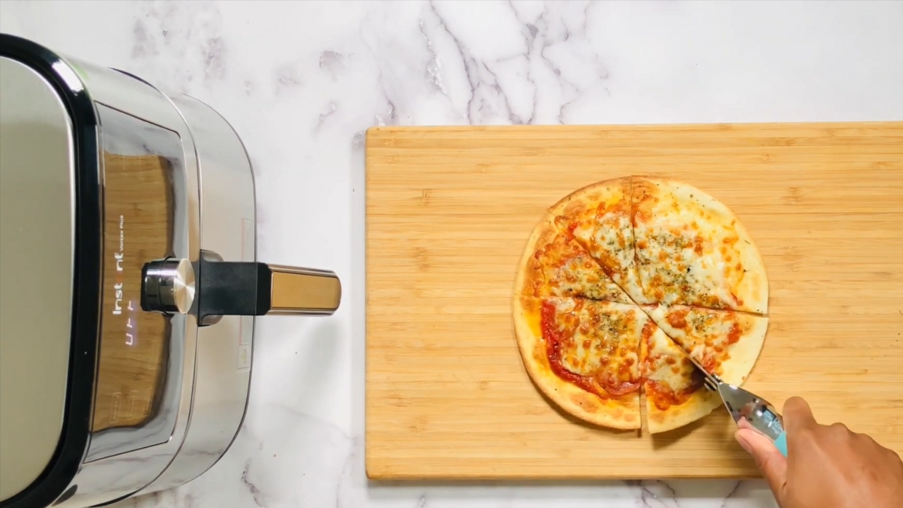 Hand Using a Pizza Cutter to Slice a Crispy Tortilla Pizza Made in An Air Fryer
