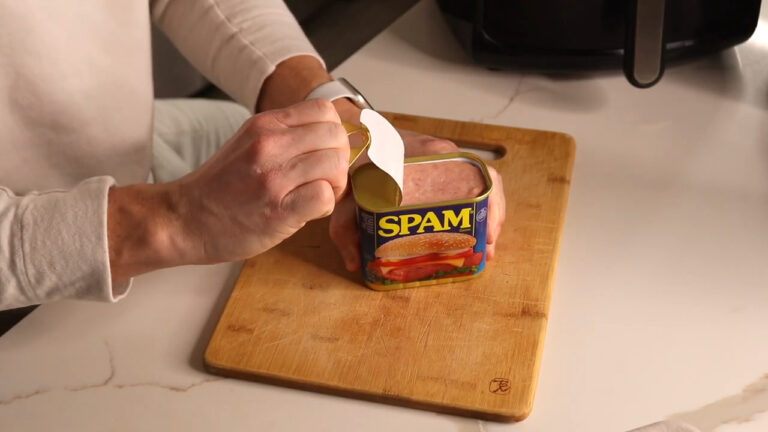 Person opening a can of SPAM on a wooden cutting board