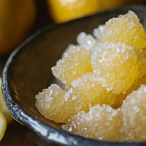 Close-up of candied citron pieces in a bowl with fresh lemons in the background