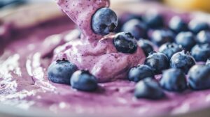 Close-up of blueberry cheesecake batter being poured, topped with fresh blueberries