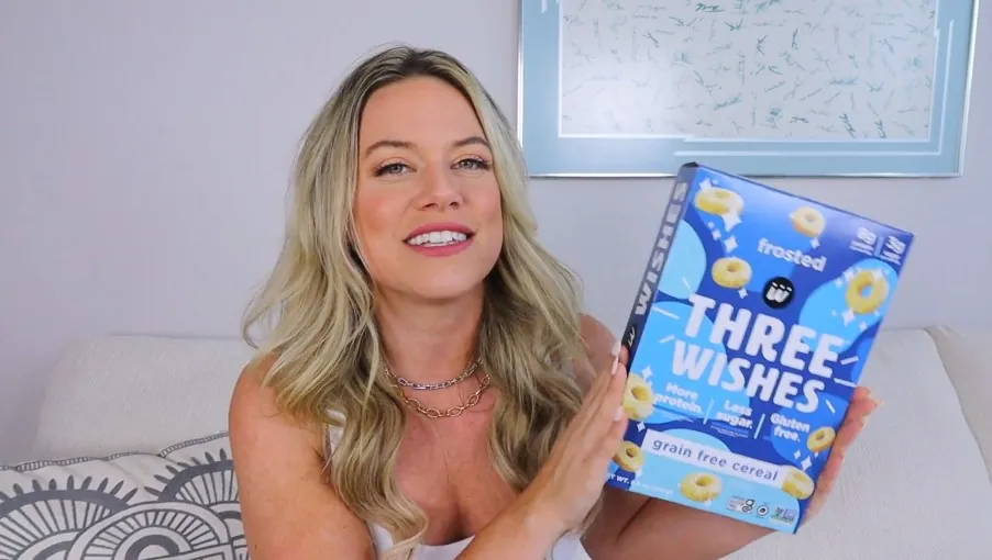 Blonde woman holding blue box of Three Wishes cereal