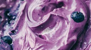 Close-up of creamy, purple blueberry yogurt with fresh blueberries mixed in.