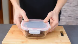 A Person Sealing Homemade Protein Bars in An Airtight Container to Chill and Set