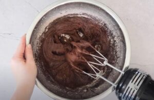 Rich, dark chocolate batter is being mixed in a large bowl