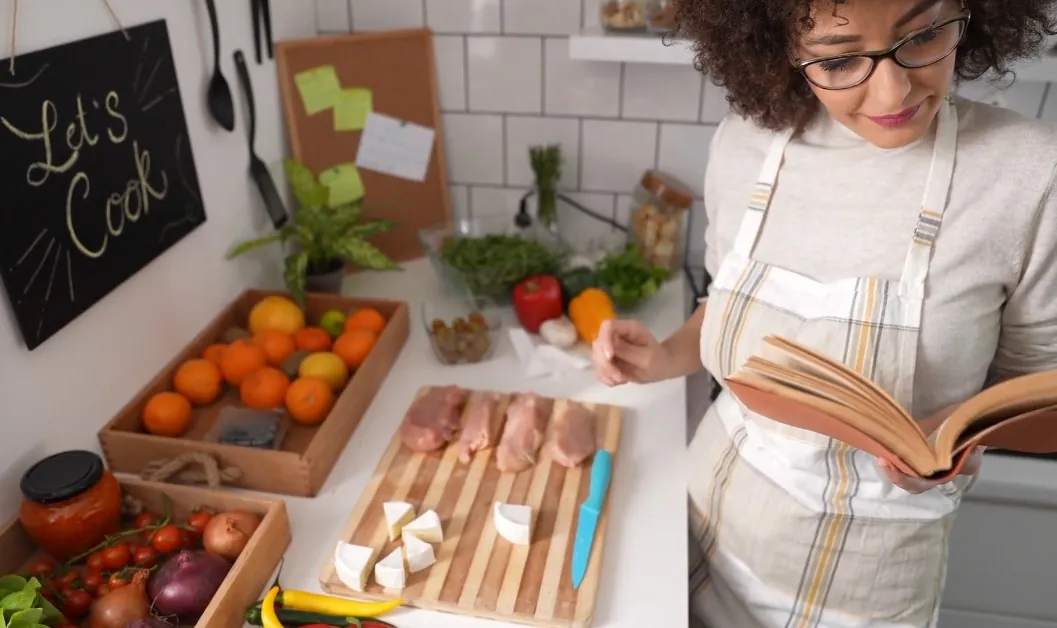 Woman meticulously prepares ingredients for a meal, consulting a recipe book